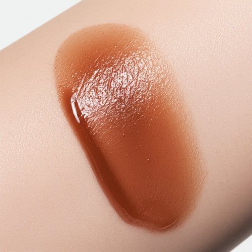 Natural skin swatch of Kalee Beauty Brown 2-in-1 Lip Oil & Cheek Tint showing sheer, dewy pigment on skin tone.